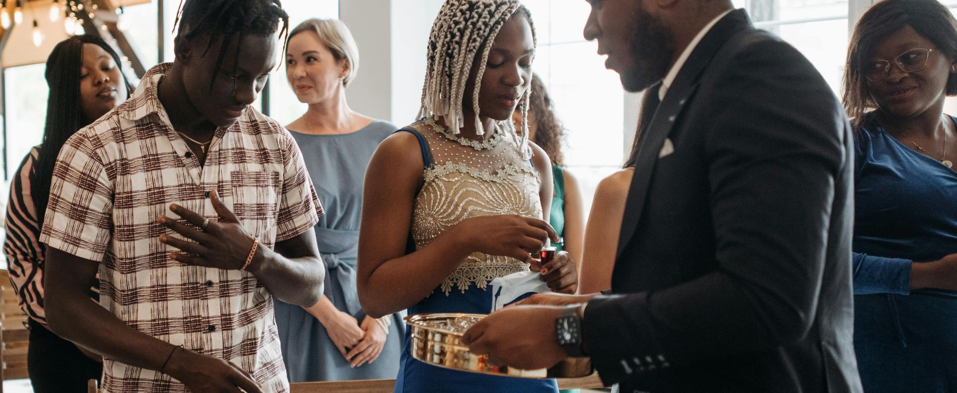 A diverse group of adults partakes in a communion ceremony inside a church.