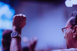 A man raises his fist in celebration or protest at a vibrant outdoor event.