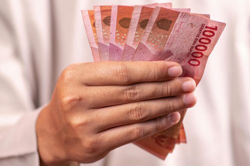 Close-up of a hand holding Indonesian Rupiah banknotes, symbolizing finance and currency exchange.